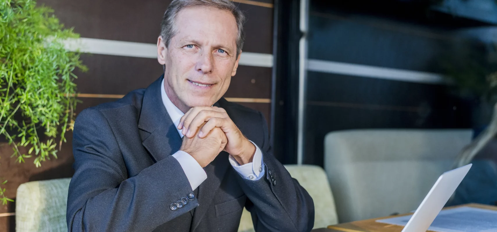 Cadre dirigeant expérimenté en costume posant avec ordinateur portable